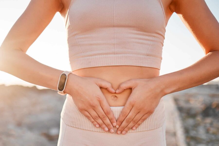 Woman, heart and hands on stomach for fitness, weightloss diet or holistic gut wellness. Closeup female abdomen, love fingers or belly emoji of body digestion, skincare and healthy exercise in nature